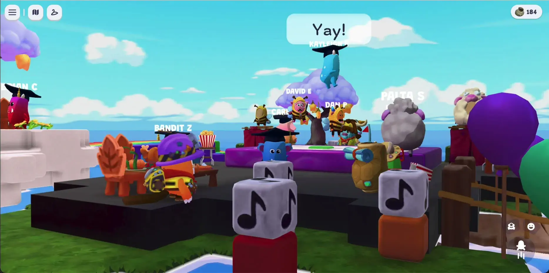 A close-up of the feast table on the graduation party island. Popcorn buckets and snacks across a long table, characters seated and standing around it, music note blocks on the platform.